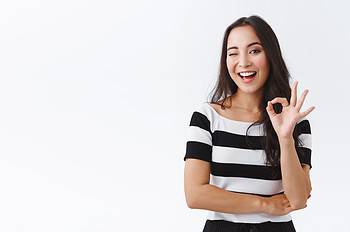 cheeky feminine asian girlfriend keep everything under control, standing relaxed and chill with no worries, showing okay, confirmation or approval gesture, wink hinting and smiling, white background